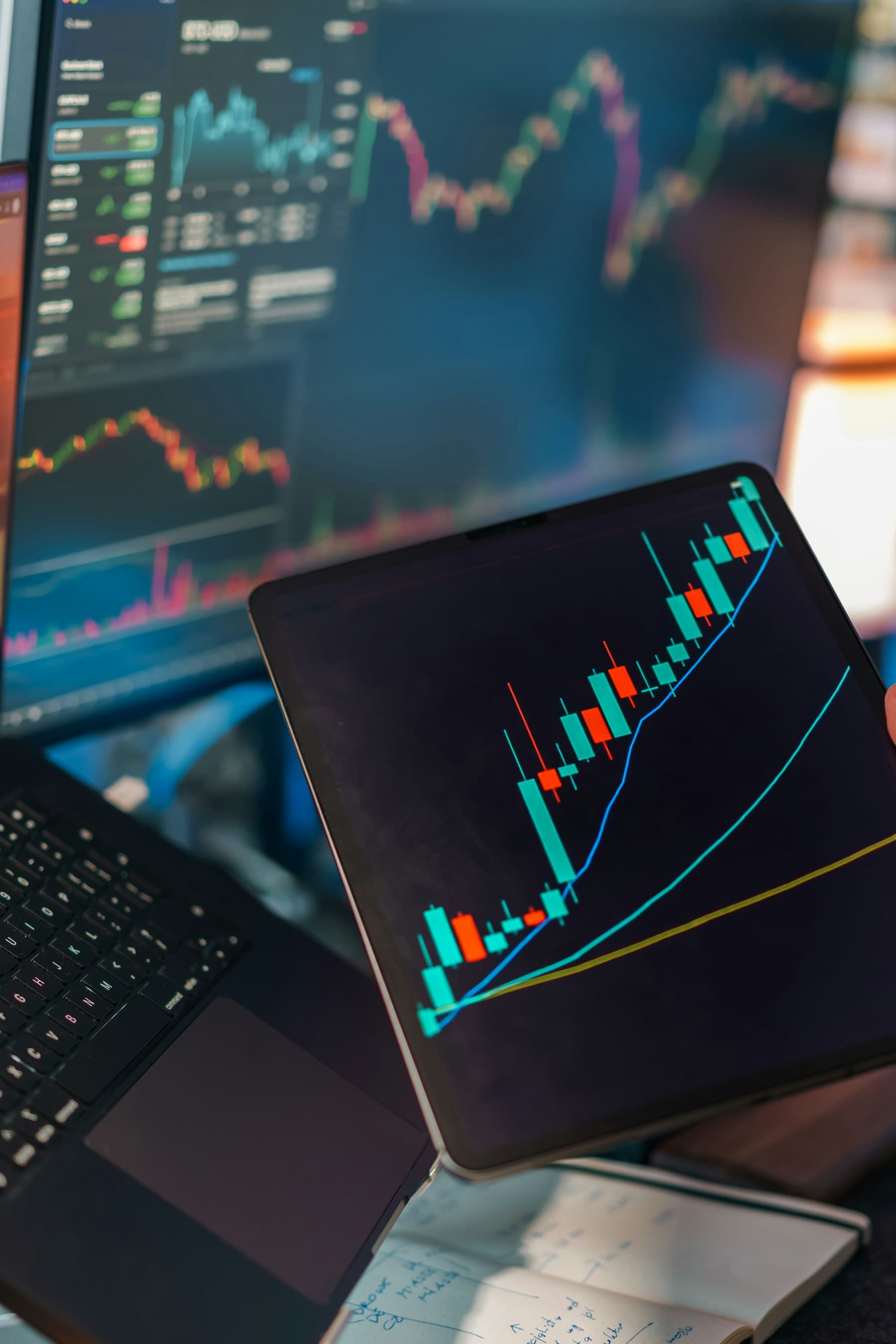 Trading charts displayed across a laptop, monitor, and tablet during market analysis